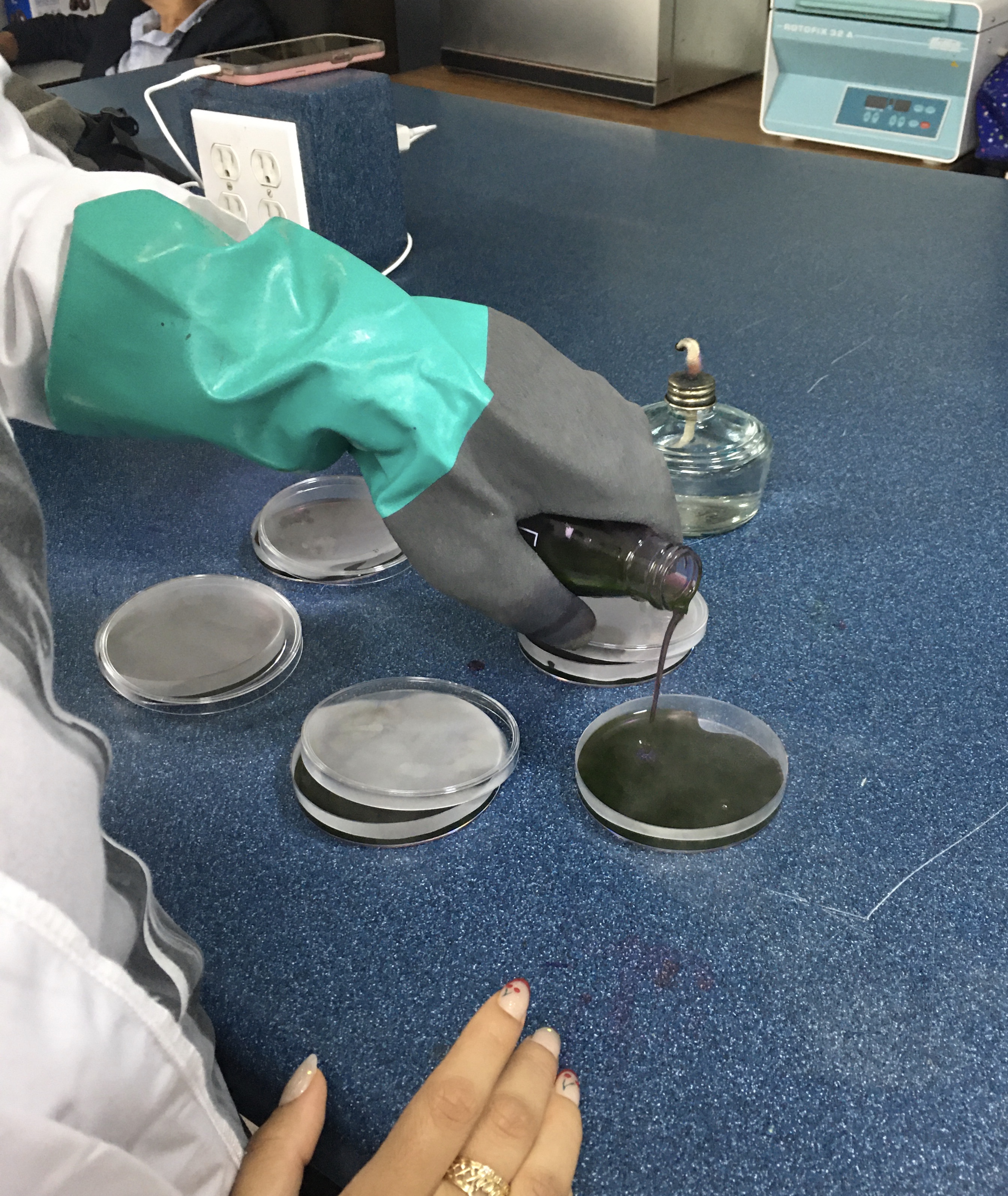 Vertido del EMB Agar en placas de Petri dentro de la zona estéril creada por el mechero.